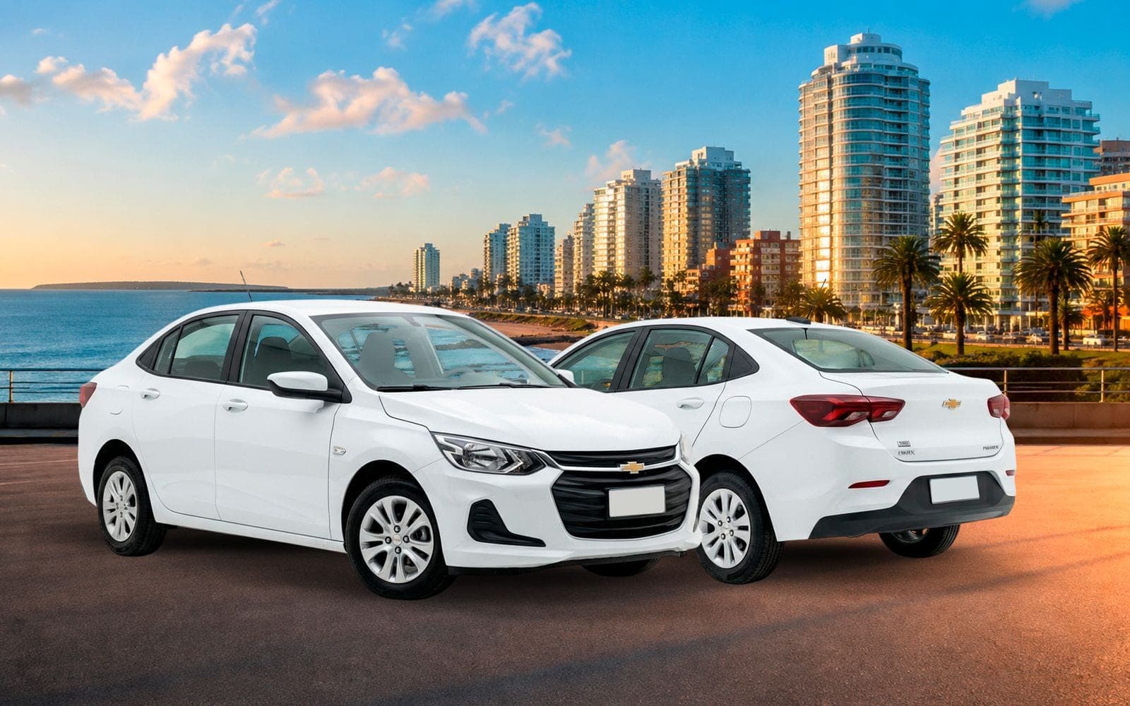 Chevrolet Onix Plus blanco, de frente y de atrás, con la playa y los edificios de la costa de Montevideo detrás