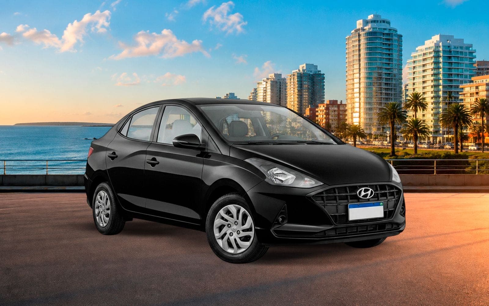 Hyundai HB20 sedán negro de frente y tres cuartos, con la playa y los edificios de la costa de Montevideo detrás