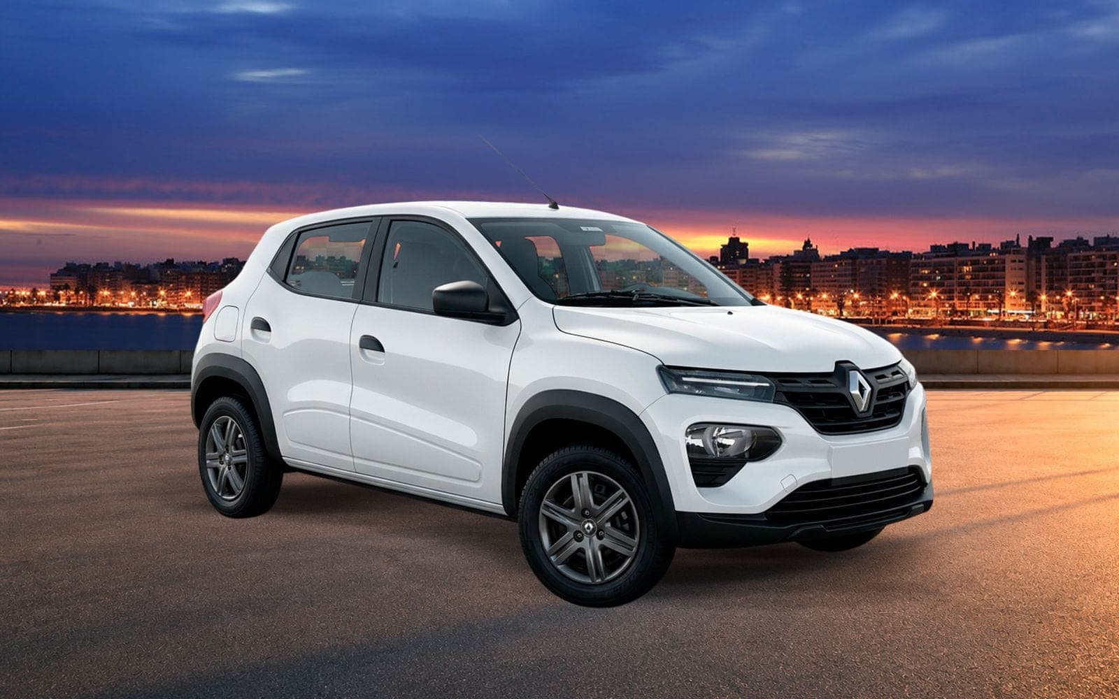 Renault Kwid blanco de frente y tres cuartos, con la costa de Montevideo iluminada al anochecer detrás